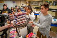 high school students stack books in a physics class