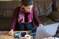 Woman working at home on her laptop and other devices