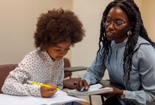 Photo of black female teacher helping a student