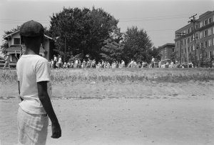 Boy stares at white rioters protesting the desegregation of schools in Arkansas.
