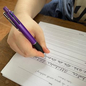 Student writing cursive with pen