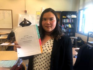 A student holding up a handout for a mock trial, marked with multicolored sticky notes