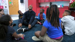 A teacher at Fall Hamilton Elementary School sitting in the middle of a circle of students.