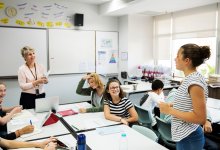 High school student standing and speaking in class to teacher