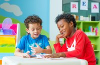 Two kindergarten students reading a book together