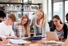 Teacher working with group of high school students on project