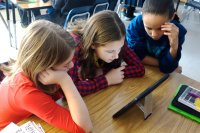 Three middle school students working on a tablet together