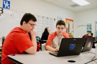 Two high school students working on a laptop together