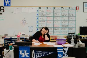 A teacher works at her desk in a classroom