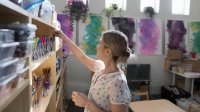 A teacher organizes shelves full of school supplies in her classroom