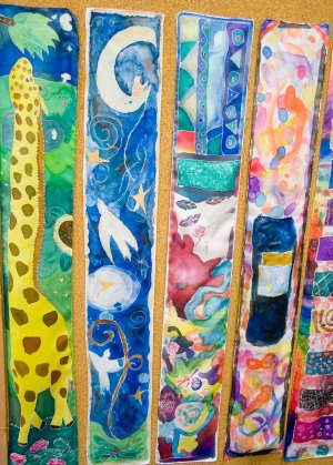 Five long sheets of watercolor paper featuring assorted student art. The first painting is of a giraffe, the second is of doves on a night sky, and the remaining three are colorful abstract expressionist pieces.