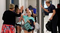 Teacher gives girl a high five in school hallway