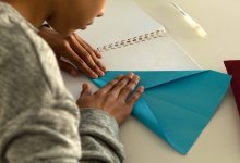 Child making paper plane at table