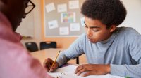 Teacher helps high school student work on project