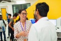 Teachers talking in a library with students in the background