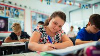 Middle school girl writing in classroom