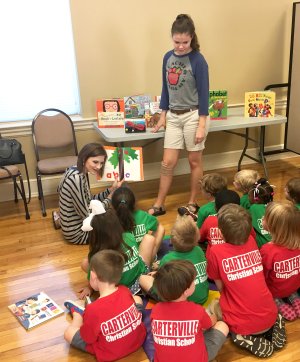 Petal High school students reading to a group of pre-schoolers.