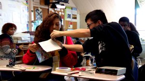 Students working together on a project with paper, tape, and scissors