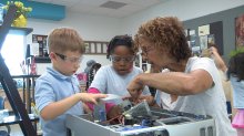 Teacher works with young children to take apart a computer.