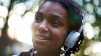 Black teen with headphones on while outside