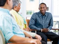 Young man speaking with two adults sitting in semi circle