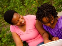 Woman and girl sitting close together looking at a binder