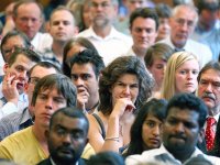 A closeup of a large group of teachers standing shoulder to shoulder in a room. They are all looking in the same direction with a reflective look on their faces.