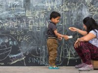 photo of a young person and adult in front of a chalkboard