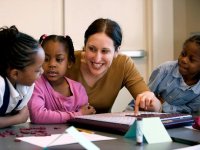 A teacher working with three little kids