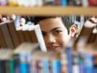 Boy looking through books in library stacks