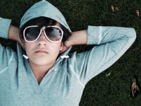 Boy in a hoodie wearing sunglasses laying on the grass