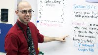 Man wearing glasses standing in front of a white board