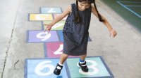 A girl plays hopscotch, unconsciously drawing on natural math capabilities.