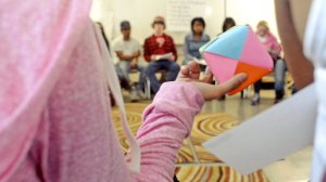 Students in a circle pass a talking piece, a paper cube.