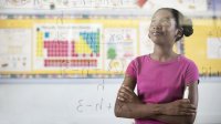 A girl looks confidently at a math problem on the board. 