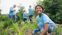 A girl in a blue shirt works in the garden