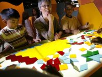 Kids and adult sitting around a table with geometric puzzle pieces