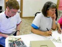 Two teachers are sitting in a classroom, calculating money.