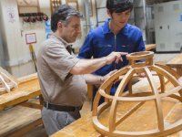 Man pointing out something to boy in wood shop