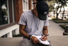 Male student sitting outside writing in a notebook