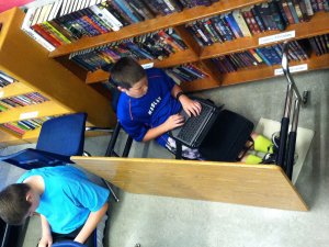 Students sit on the floor in class while working.