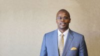 Photo of Antwan Wilson, a black male educator smiling in a suit.