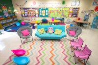 A colorful classroom with couches, collapsible desks, and scoop chairs