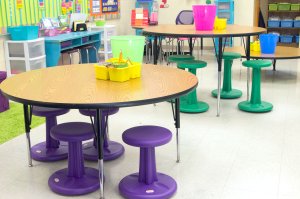 Circular tables at different heights in a classroom.