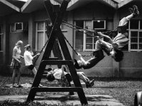 Four students are swinging on a swing set, and another student is standing by one of them.