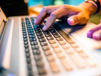 A closeup of a person's hands on a laptop keyboard.