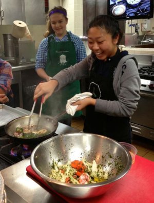 Student Bailey Lum pan-frying some vegetables.