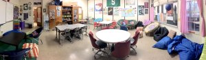 A deskless classroom filled with tables and non-traditional furniture like bean bags.