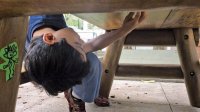 A boy looks under a table at school for a hidden game token.