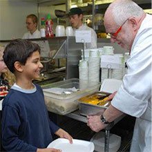 A photo of chef Robert 'Bobo' talking with a young student.